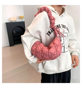 Detail of pink quilted crescent bag with ruffled shoulder strap worn by model
