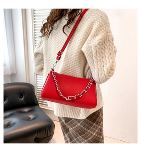 Chic red litchi texture PU crossbody bag with silver chain worn by a model in a white sweater