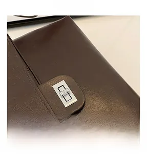 Close-up of the silver metal rotating lock and leather texture on a dark brown handbag