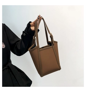 Detail of minimalist dark brown PU leather bucket bag with metallic buckle and vertical trim