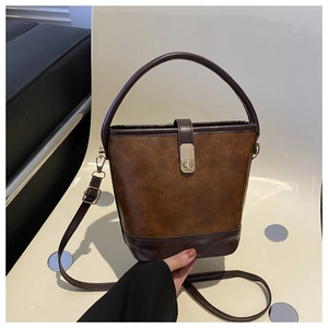 Detailansicht der Vintage-Beuteltasche in Bi-Color mit goldener Schließe auf einem Stuhl