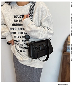 Detail of black PU leather crossbody bag featuring a patterned wide fabric shoulder strap