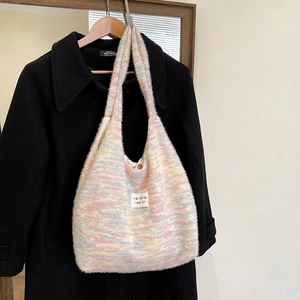 Close-up of rainbow knit tote bag with brand label and magnetic metal snap closure