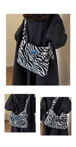 Detail of soft zebra print plush shoulder bag featuring a unique blue brand label accent