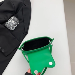 Detail of bright green handbag featuring dual silver magnetic buckles and black lining