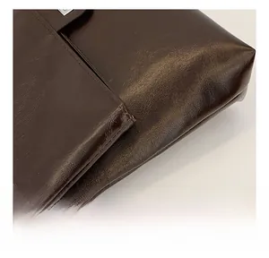 Close-up of premium dark coffee PU leather texture with detailed stitching and folds