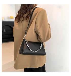Detail of black lychee grain leather handbag with silver chain and leather shoulder strap