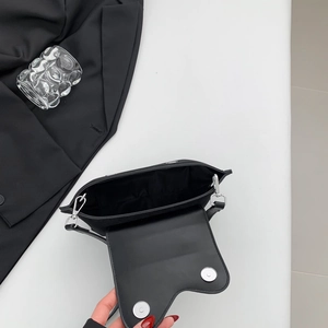 Detail view of the black crossbody bag with asymmetric flap and double silver magnetic buckles