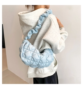 Close-up of light blue quilted half-moon shoulder bag showing soft padded texture