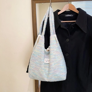 Close-up of rainbow striped knit tote bag with brand label and metal snap button
