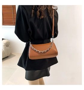 Rear view of model wearing a brown lychee pattern PU leather bag with silver chain detail