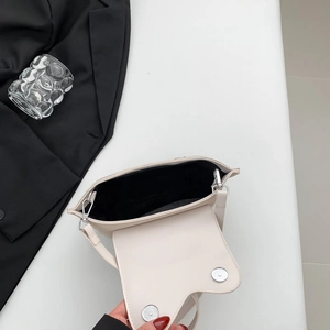 Detail view of cream PU leather handbag with silver rotating buckle and black lining