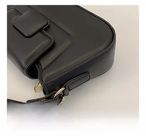 Detailed close-up of golden metal swivel hook and hardware on black leather handbag