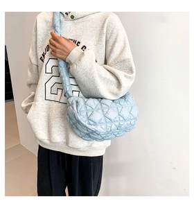 Close-up of a light blue quilted crossbody bag featuring a half-moon shape and wide strap