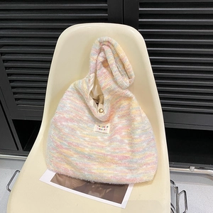 Detail of macaron striped knit tote with plush texture and metallic magnetic closure