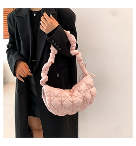 Close-up of pink quilted cloud bag with textured pleats and sleek metal zipper detail
