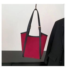 Detail view of burgundy tote bag with black leather trim and golden metal adjustable buckle