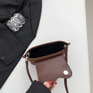 Detail view of coffee brown crossbody bag showing silver magnetic closure and interior lining