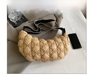 Dettaglio della borsa a mezzaluna in nylon trapuntato con tracolla larga e telefono