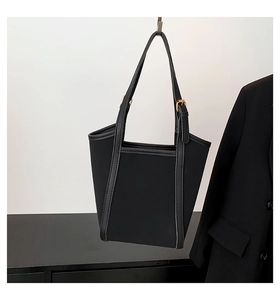 Detail showing high-quality black canvas tote bag with premium leather edge and metal buckle