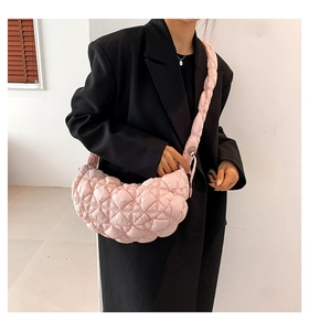 Detail of light pink quilted puffer crescent bag with diamond stitching and wide strap