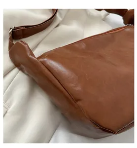 Detail view of caramel PU leather bag texture with wide strap and silver metal buckle