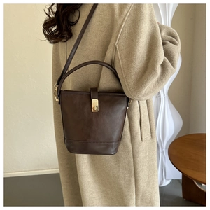 Detailansicht dunkelbraune PU-Eimertasche mit Goldverschluss am Model mit Wollmantel