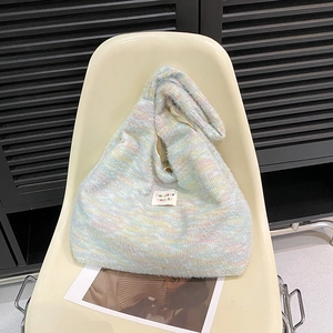 Close-up of knit tote bag featuring pastel stripes and white fabric brand label