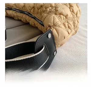 Dettaglio dei rivetti premium e attacco in pelle su una borsa in nylon beige trapuntata