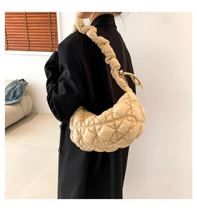 Detail view of beige quilted cloud bag with puffy ruffles and wide shoulder strap