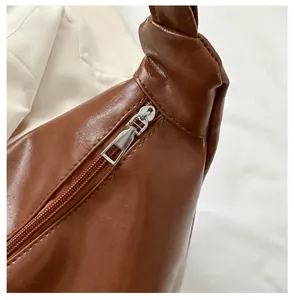 Detail of brown lychee grain PU leather bag with smooth metal zipper and knotted strap