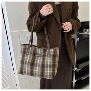 Close-up of wool plaid tote bag with brown leather handles and classic check pattern