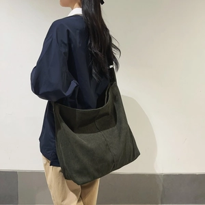 Dettaglio di una borsa hobo grande in velluto a coste verde scuro indossata da modella