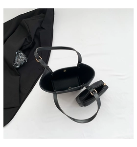 Flat lay of a black minimalist bucket bag set with inner pouch and gold hardware accents