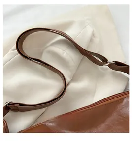 Detailed close-up of premium brown PU leather texture and silver zipper on handbag