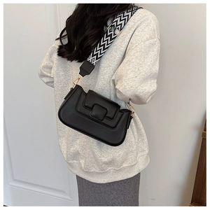 Detail view of black PU leather shoulder bag with wide geometric patterned strap on model