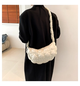 White quilted half-moon shoulder bag shown on model with puffy ruched texture and strap