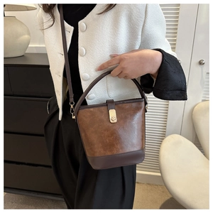 Detail einer dunkelbraunen PU-Leder Eimertasche mit goldenem Metalldrehverschluss