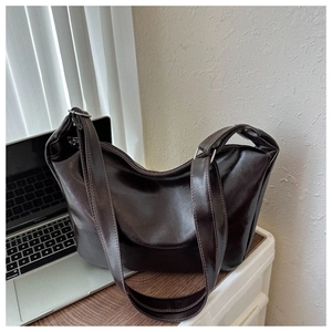 Detail of soft dark brown faux leather tote bag with silver hardware on a desk