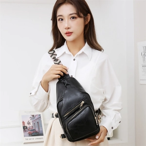 Detail of black PU leather crossbody bag with woven strap and golden hardware accents