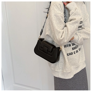 Detail view of black PU leather handbag featuring a stylish black and white geometric strap