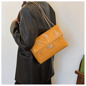 Close-up of yellow PU leather shoulder bag featuring silver chain strap and twist lock