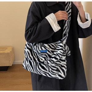 Close-up of zebra print faux fur shoulder bag with soft plush texture and blue brand label