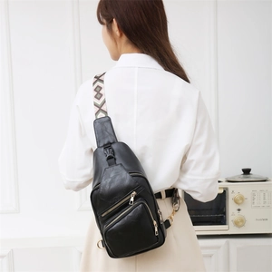 Close-up of black PU leather crossbody bag with golden zippers and geometric woven strap