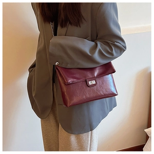 Detail of burgundy PU leather envelope bag with metal buckle on grey blazer outfit
