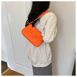 Model wearing a bright orange PU leather shoulder bag over a minimalist grey and white outfit