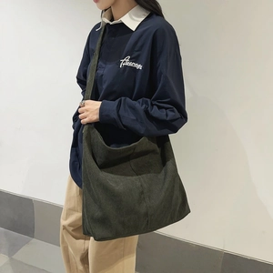 Borsa hobo in velluto a coste verde scuro abbinata a camicia blu e pantaloni beige