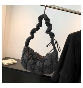 Detail of black quilted puffer shoulder bag featuring unique pleated bubble strap texture