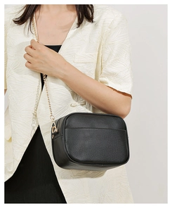 Close-up of black lychee grain leather camera bag with gold chain and front pocket