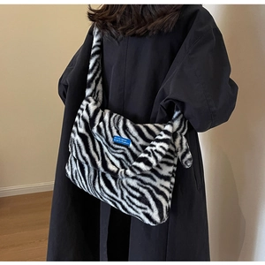 Detail view of winter plush zebra print shoulder bag with a blue decorative label accent